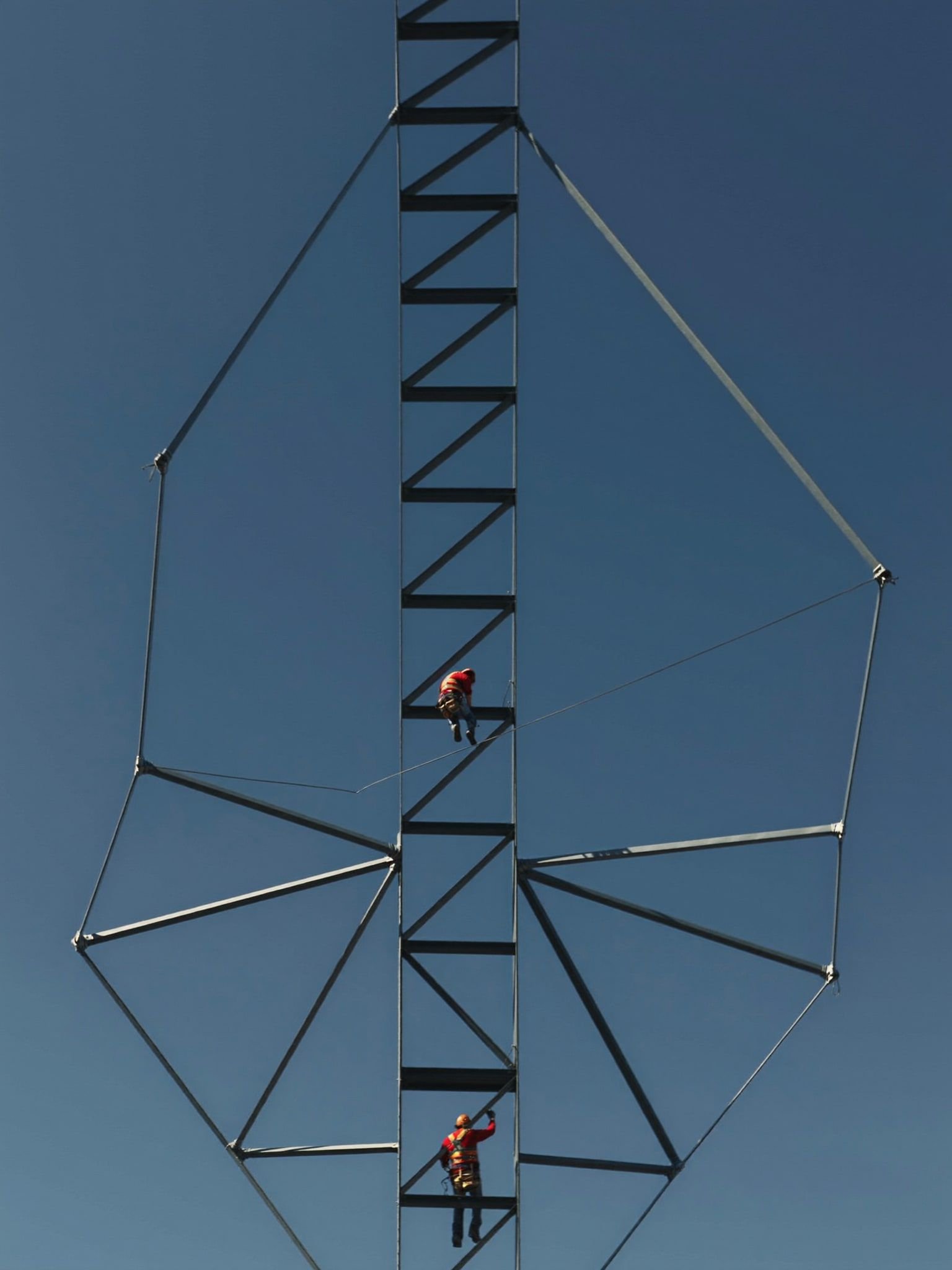 Ironworker walking a steel beam on a structural frame against a hard blue Texas sky