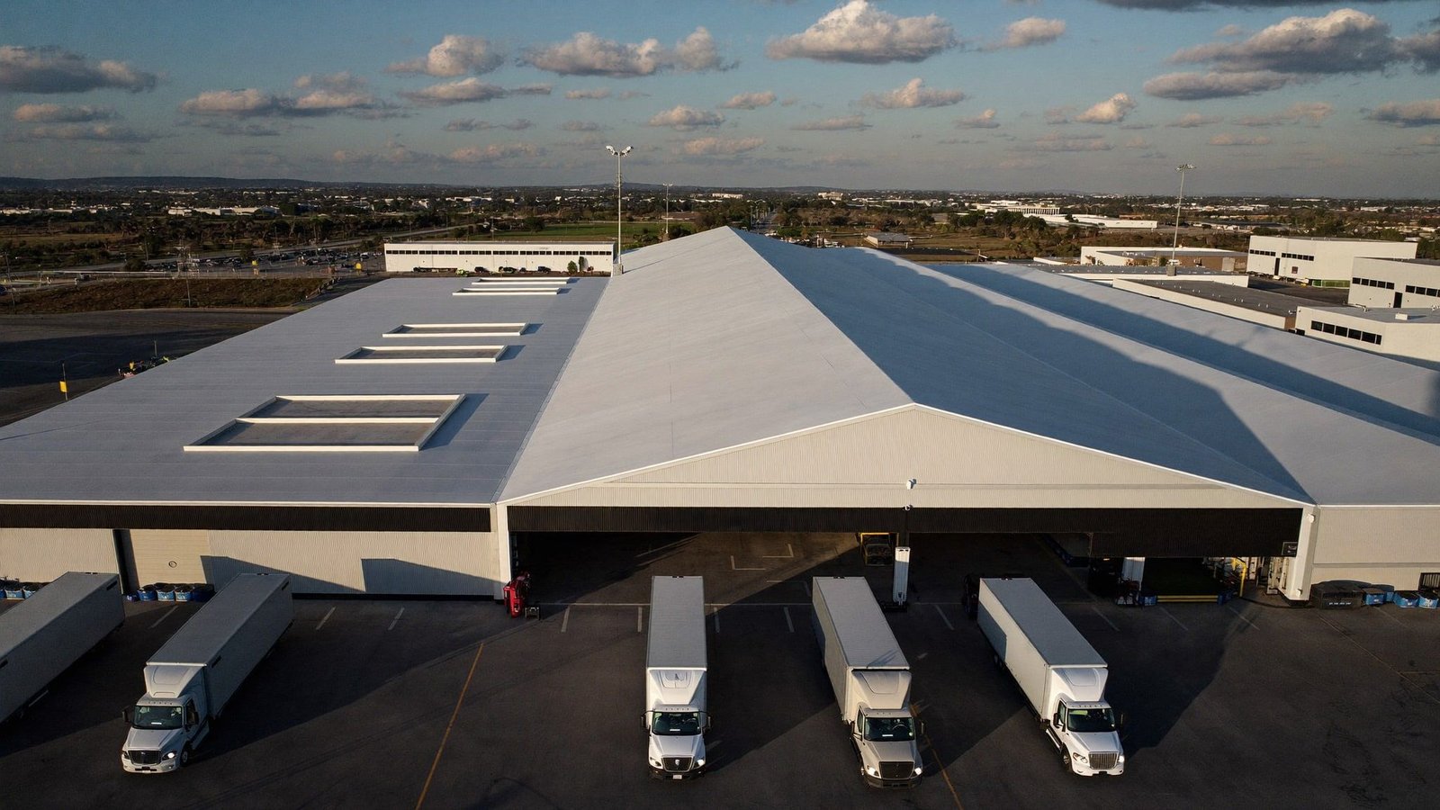 Aerial view of a completed distribution center outside Dallas at dusk, trucks parked at the loading docks