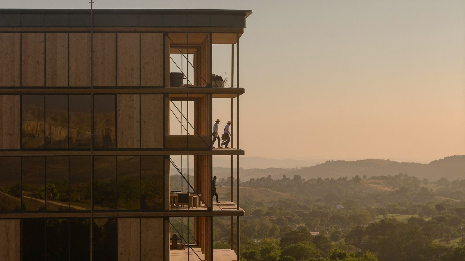 Mass timber and steel office under construction in Austin at golden hour, Hill Country horizon behind