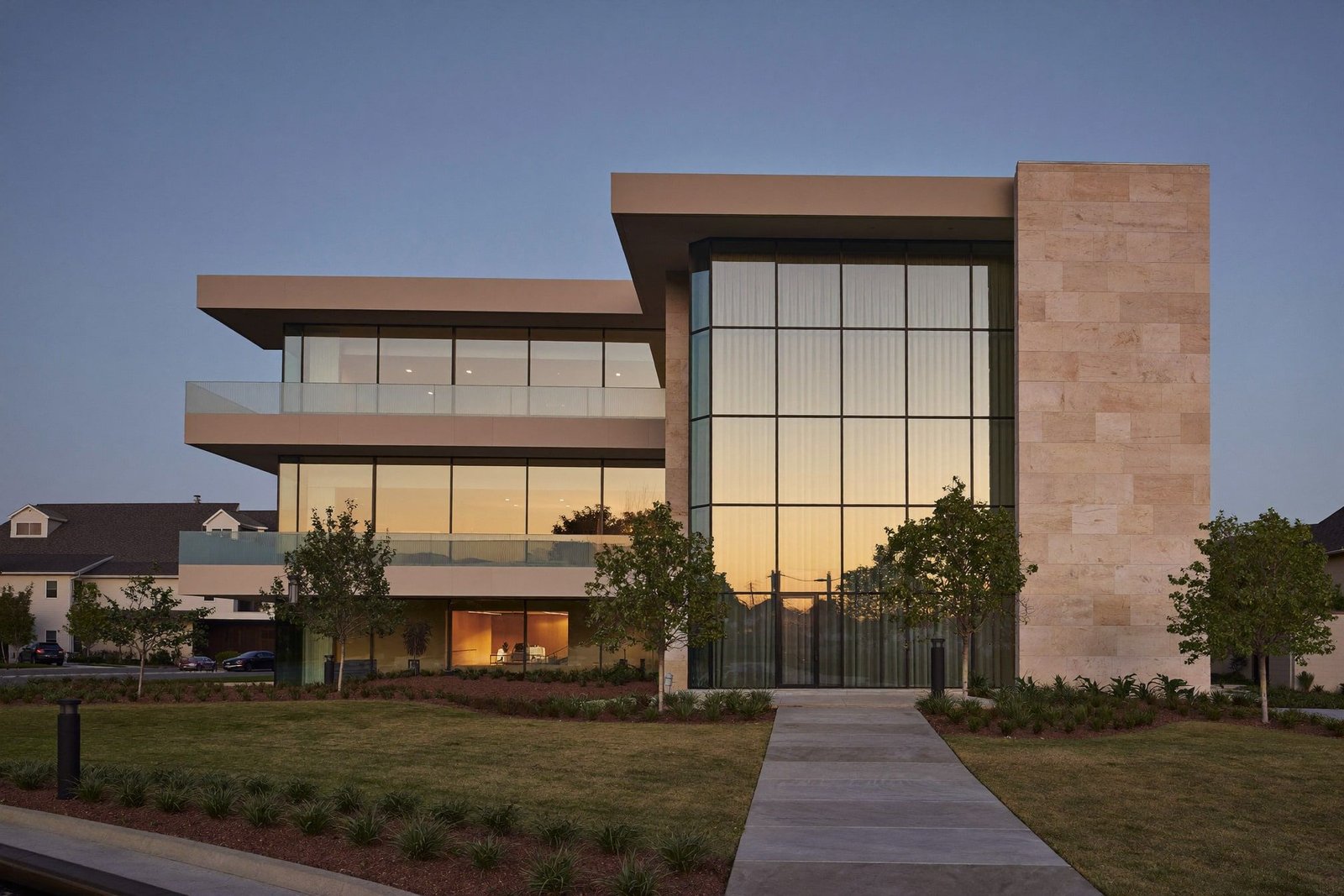 Three-story medical office building at blue hour, glass curtain wall and limestone above a landscaped entry