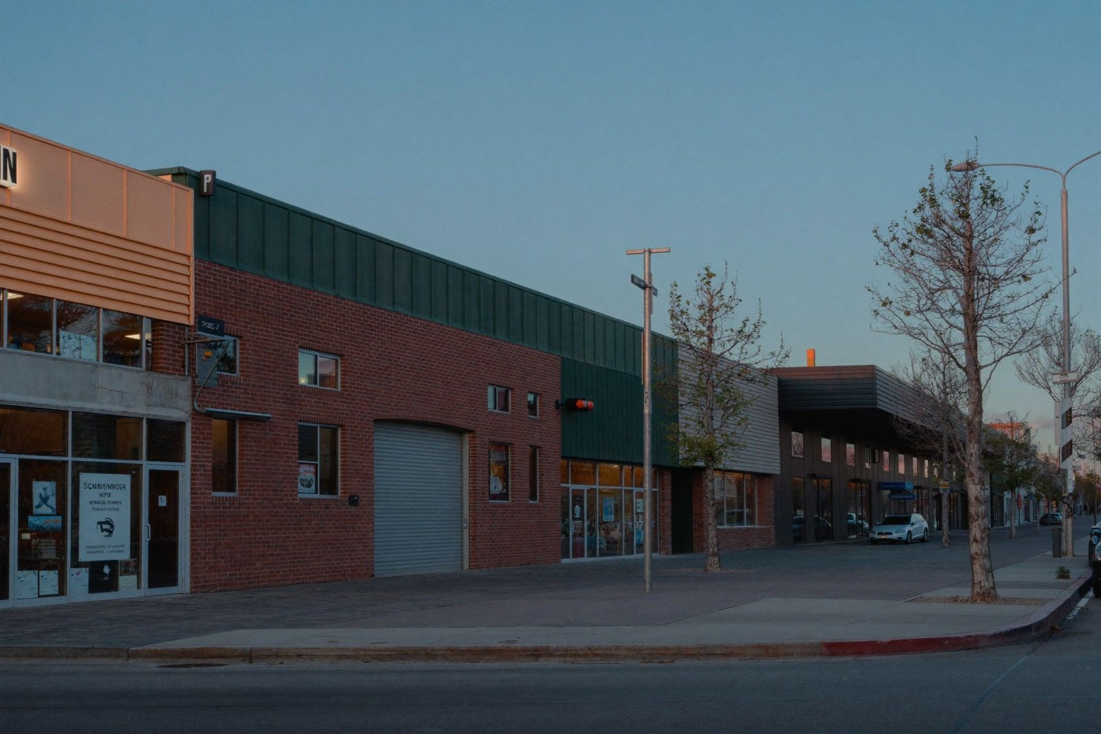 Brick and steel mixed-use retail shell at blue hour along a wide San Antonio sidewalk
